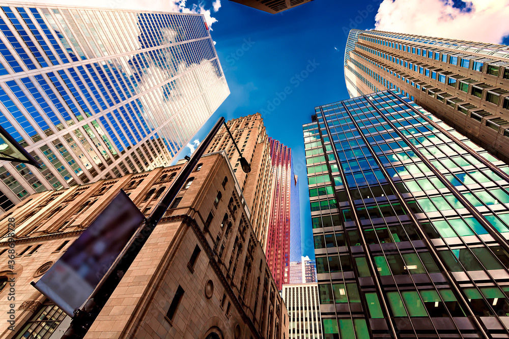 Looking up at skyscrapers reflecting clouds in their windows.