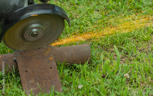 cutting metal on grass with a hand tool. sparks flying from iron. selective focus