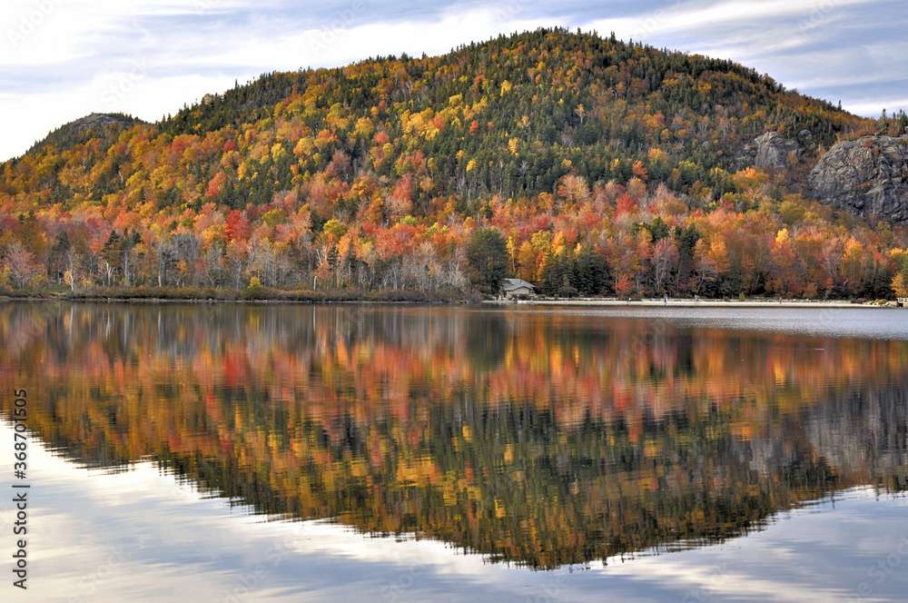 Late autumn afternoon in New Hampshire’s Franconia Notch State Park. Colorful fall foliage reflecting on calm surface of Echo Lake. Artists Bluff, with open ledges, at far top right.