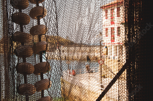 View of water and building through fishing net in Cudillero, Spain photo