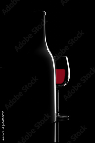 Backlit bottle and glass of red wine on black background. 3d illustration.
