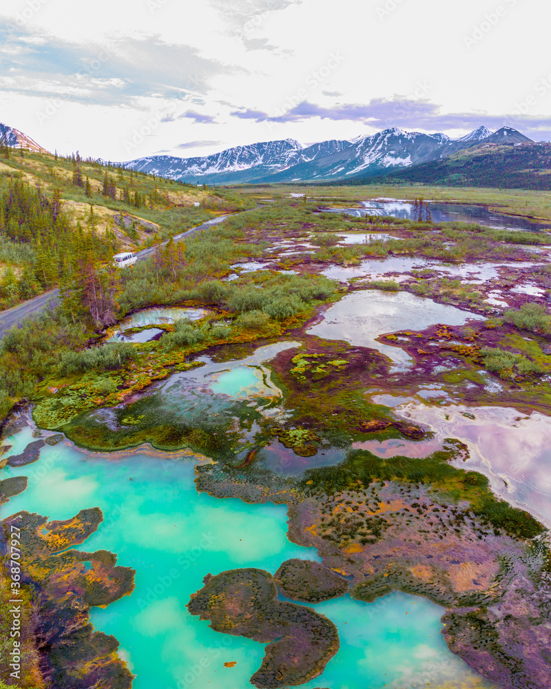 Incredible drone shot of isolated & wild Canadian landscape with snow capped mountains & turquoise lake and pristine creeks. 