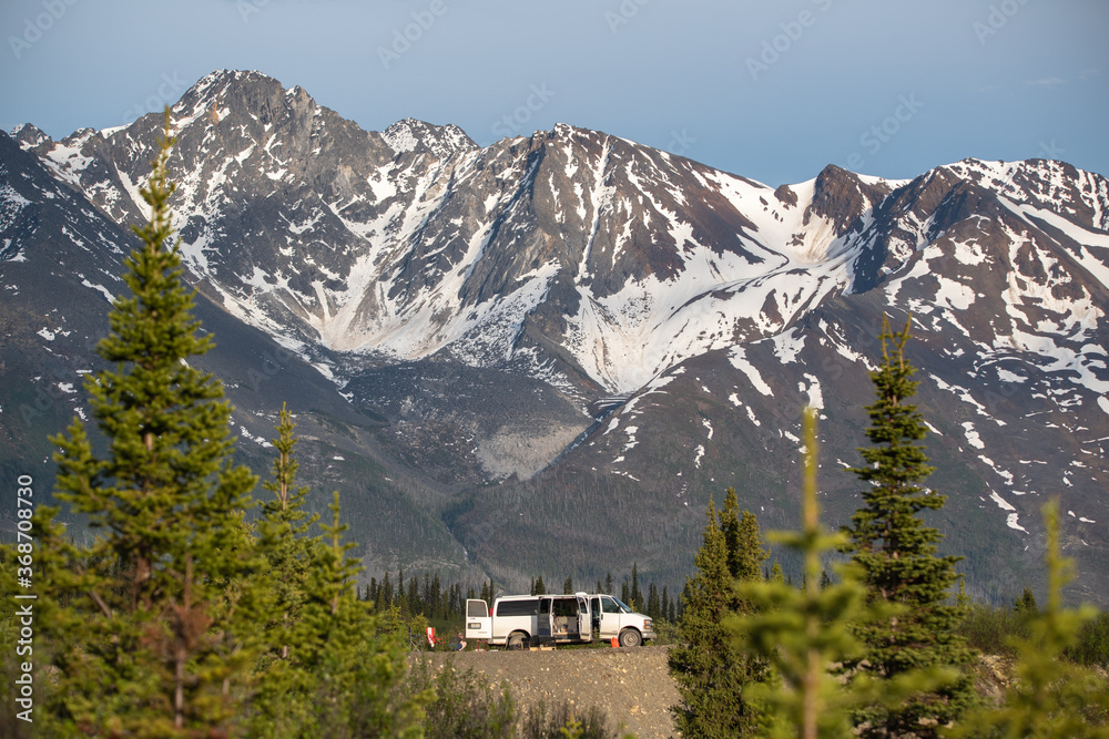 Van life camping in the amazing Yukon Territory with magnificent background mountains in huge proportions Taken in the summer time with snow on the surrounding mountains. 
