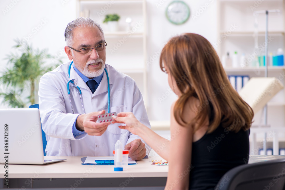 Obraz premium Young woman visiting old male doctor