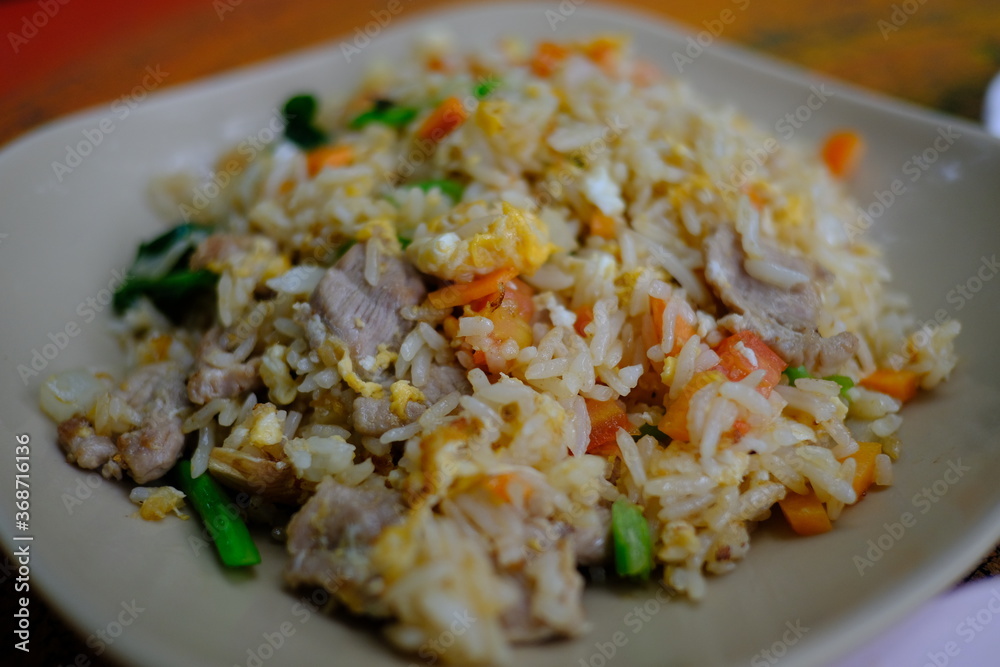 Fried rice with vegetables, broccoli, peas and eggs in a white bowl.
