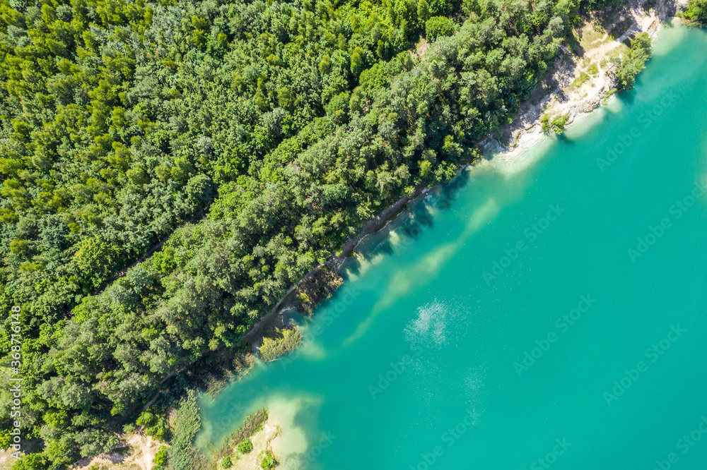 aerial top view of a calm quarry lake with coast covered by green forest. summer landscape
