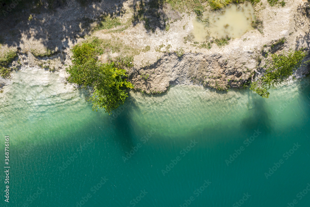 abandoned limestone quarry flooded with turquoise water. aerial drone photo looking down
