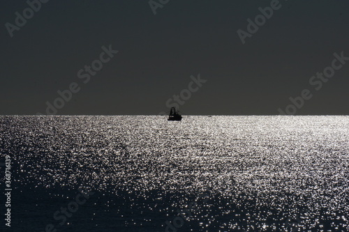 The glare on the ocean from sun contributing to this scene. photo