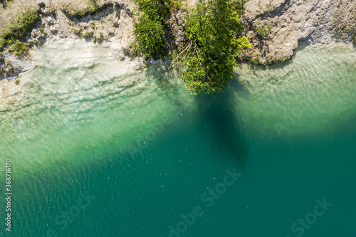 artificial lake with pure deep green water, and white shore in abandoned limestone quarry. drone point view