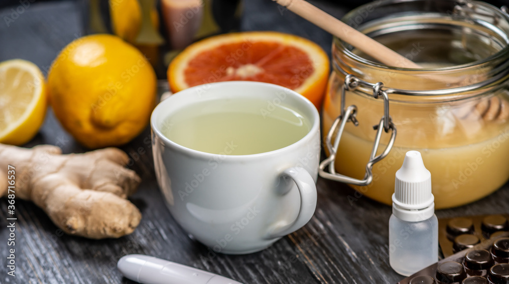 Hot tea with ginger, honey, lemon and preparations for cold and a thermometer. Concept of vitamin healthy tea for the sick Hot tea with ginger, honey, lemon and preparations for cold and a thermometer. Concept of vitamin healthy tea for the sick
