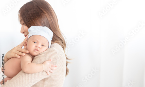 Close up beautiful young asian mother holding her newborn one month baby sleep on her shoulder. Healthcare and medical.  Lovely asian woman lifestyle mother's day concept.