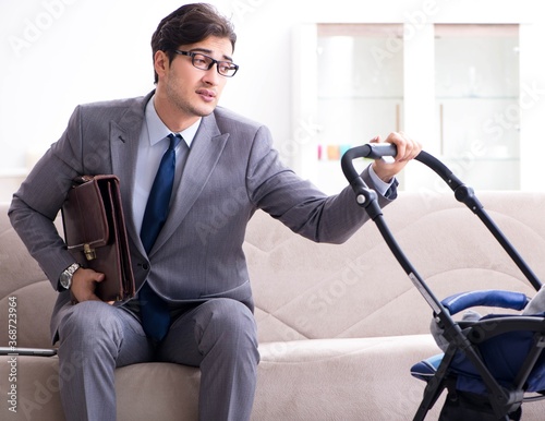 Businessman looking after newborn baby at home and teleworking