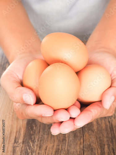 A woman hand holding fresh egg on a wooden background. High protein and Vitamin foods. Concept of healthy..