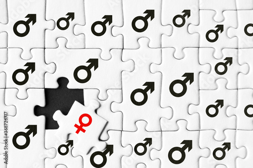 White gray puzzles with depicted male mars symbol are stacked on black background. One piece with female sign of venus located separately. Concept of gender inequality, discrimination in society.