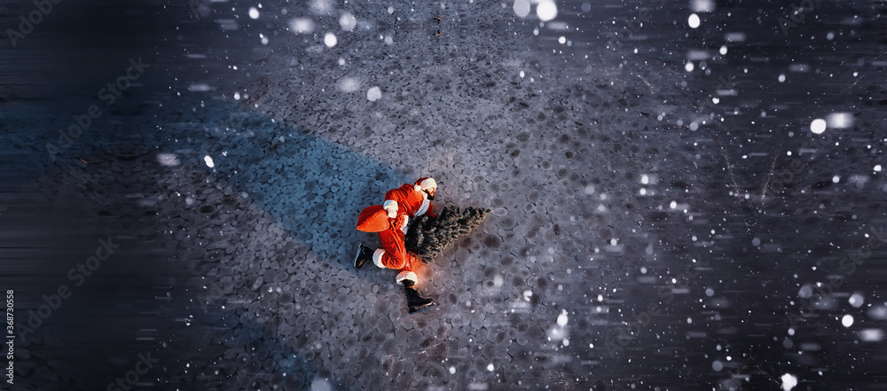 Fototapeta premium Santa Claus on ice skates goes to Christmas. Santa Claus hurries to meet the New Year with gifts and Christmas tree.
