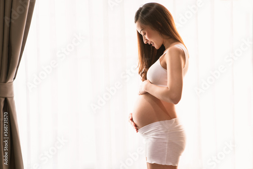 a beautiful woman pregnant in standing beside windows smiley happy and relax in bed room her with Pregnant Belly with hand touch on pregnant Belly Free Download a beautiful woman pregnant in standing beside windows smiley happy and relax in bed room her with Pregnant Belly with hand touch on pregnant Belly - GFXLoad