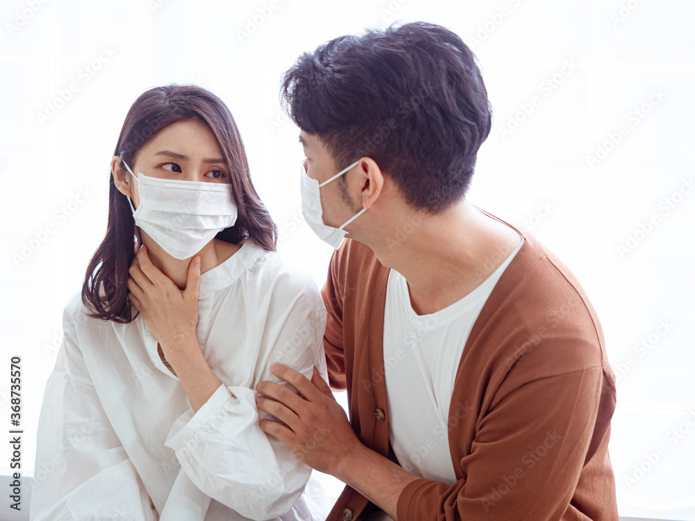 Young asian couple wearing surgical mask over white background