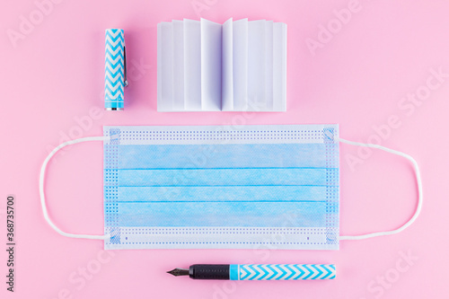 Back to school concept. School notepad, pen and protective mask. Stationery and face mask. Education during the quarantine period. Top view