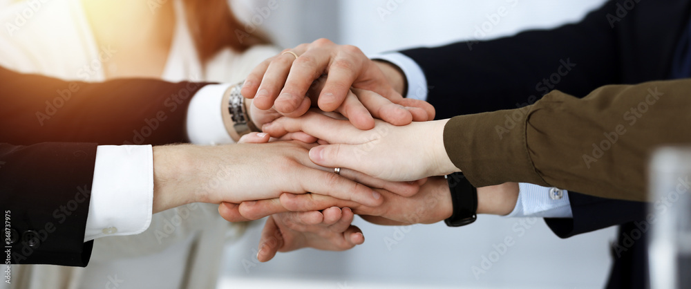 Business people group showing teamwork and joining hands or giving five in sunny office. Unknown businessman and women making circle with their hands