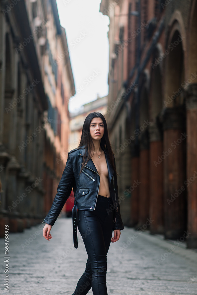 Portrait of beautiful young blonde woman wearing stylish black outfit, she smiling on urban background, happy time, Travel Concept.trendy girl in stylish sunglasses ad leather jacket in the street.