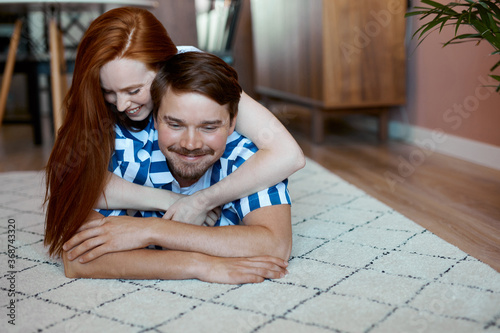 portrait of beautiful couple lying on floor, have rest, redhead woman and brunette guy enjoy spending time at home