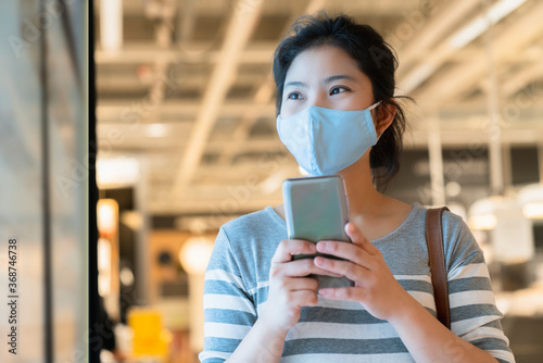 new normal after covid19 epidemic smart asian female wear protection mask hand use smartphone communication in department store new lifestyle abstract blur background