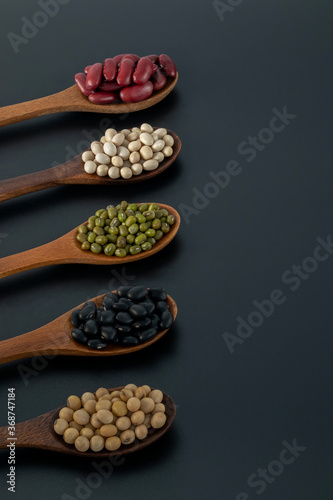 Collection of whole grains seeds isolated on black background. Healthy diet raw ingredients.