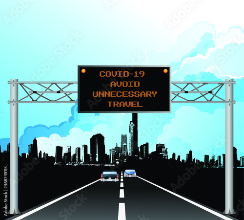 Roadway overhead digital gantry sign with COVID 19 Coronavirus avoid unnecessary travel message set against a blue cloudy sky 