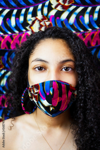 young women wearing a mask and earrings made from African materials. 