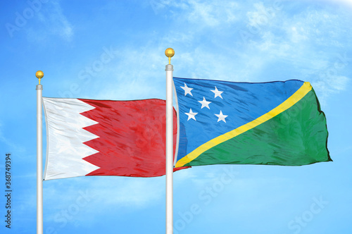 Bahrain and Solomon Islands two flags on flagpoles and blue sky