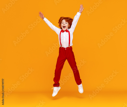 funny red-haired boy jumps on a yellow background.