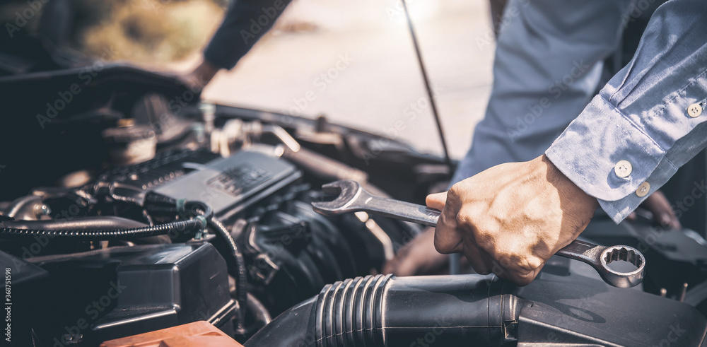 Close-up hand of auto mechanic using wrench to repair a car engine. concepts of car care fix repair service and insurance. Close-up hand of auto mechanic using wrench to repair a car engine. concepts of car care fix repair service and insurance.