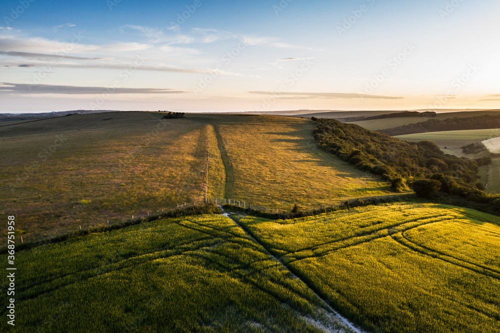 Stunning high flying drone landscape image of rolling hills in English countryside with lovely warm late evening light Stunning high flying drone landscape image of rolling hills in English countryside with lovely warm late evening light
