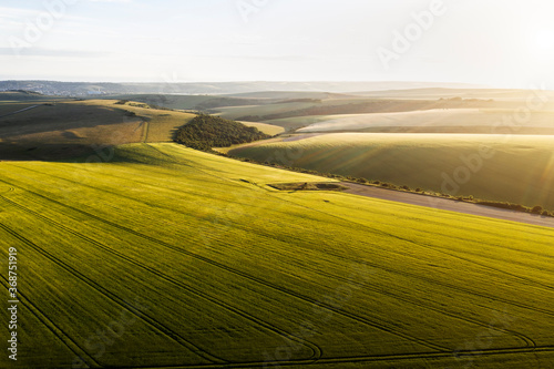 Stunning high flying drone landscape image of rolling hills in English countryside with lovely warm late evening light