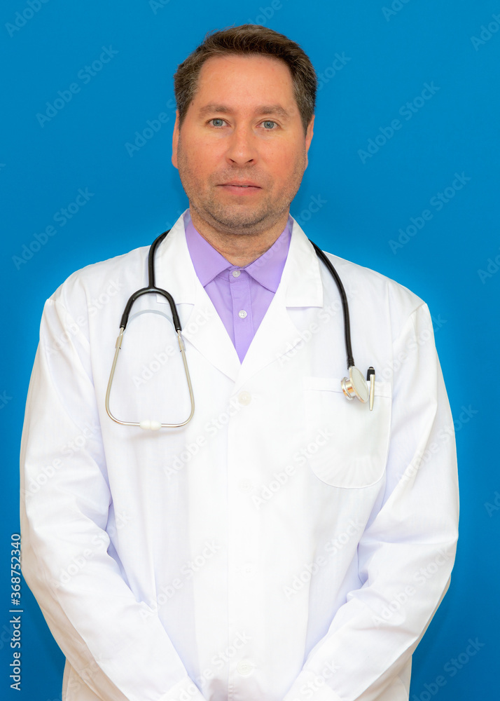 vertical photo A male doctor with a stethoscope smiling a clipboard while standing in a clinic. on light blue background vertical photo A male doctor with a stethoscope smiling a clipboard while standing in a clinic. on light blue background