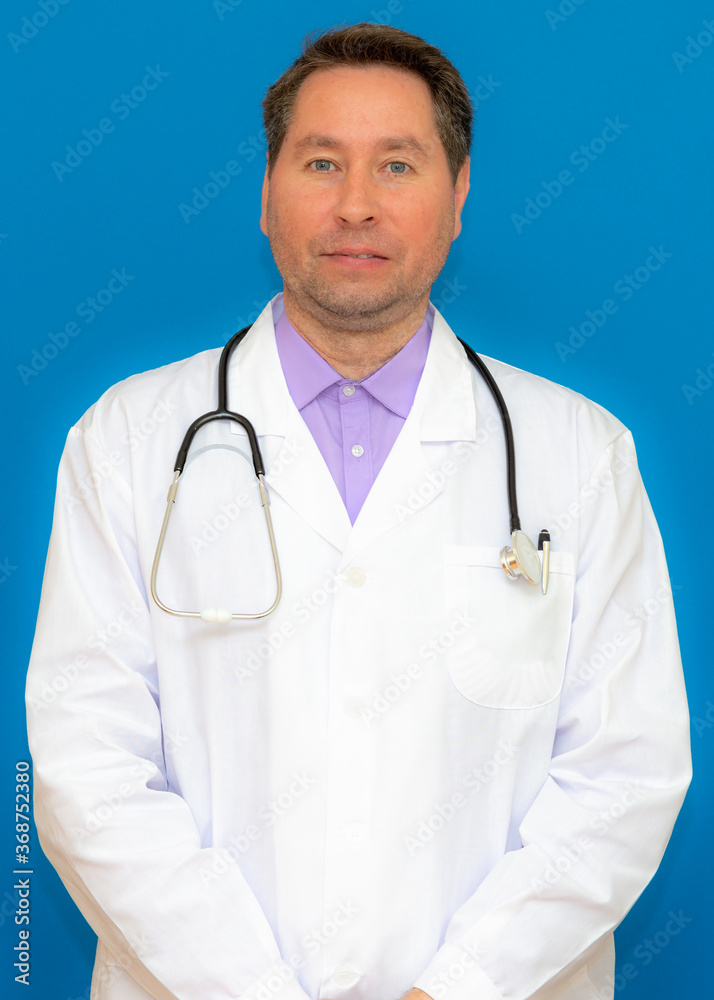 vertical photo A male doctor with a stethoscope smiling a clipboard while standing in a clinic. on light blue background vertical photo A male doctor with a stethoscope smiling a clipboard while standing in a clinic. on light blue background