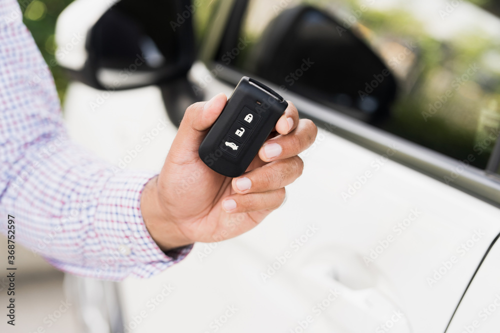 Close up car keys and remote control car alarm systems hold in hand. Young man buy the new car. Close up car keys and remote control car alarm systems hold in hand. Young man buy the new car.