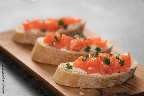 Bruschettas with salmon and cream cheese on olive wood board