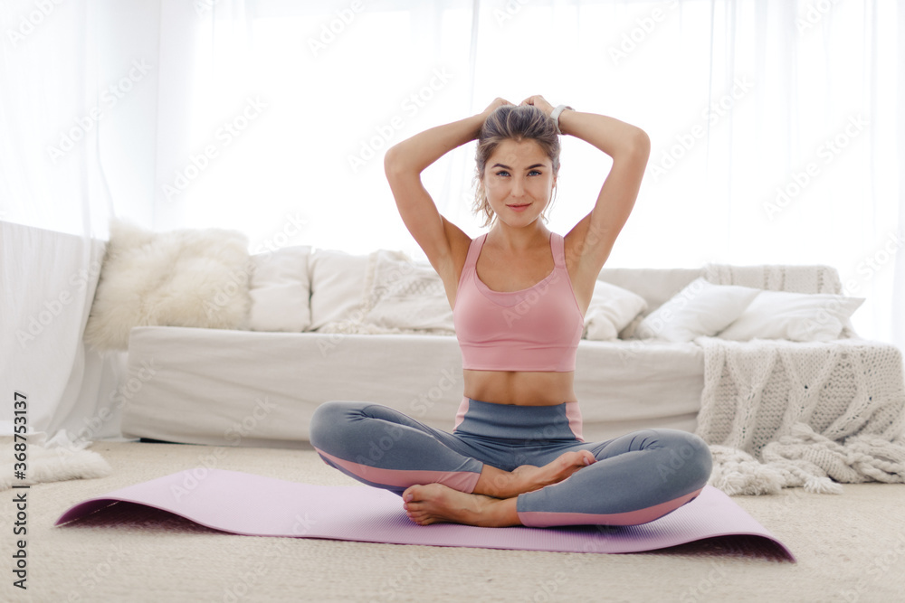 young sports girl in sportswear is engaged in yoga and stretching at home. Does isolation exercises in a bright room. healthy lifestyle young sports girl in sportswear is engaged in yoga and stretching at home. Does isolation exercises in a bright room. healthy lifestyle
