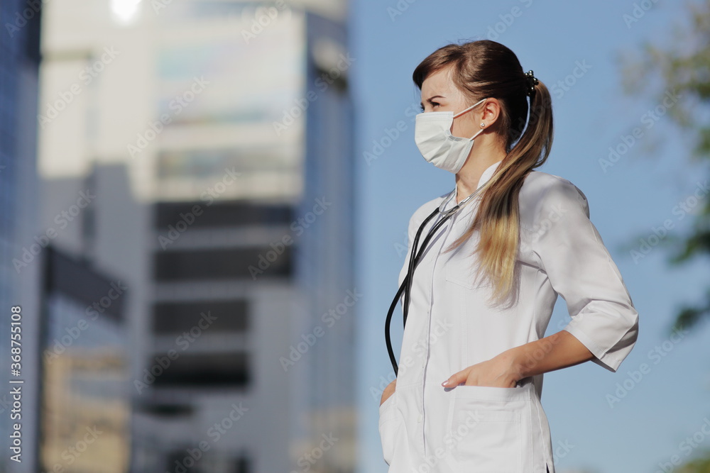 Female doctor, nurse wearing a protective face mask in the city. Skyscraper, sky Female doctor, nurse wearing a protective face mask in the city. Skyscraper, sky
