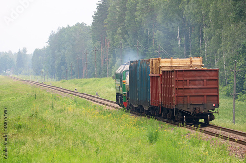 freight train pulls cars and smokes heavily in the forest