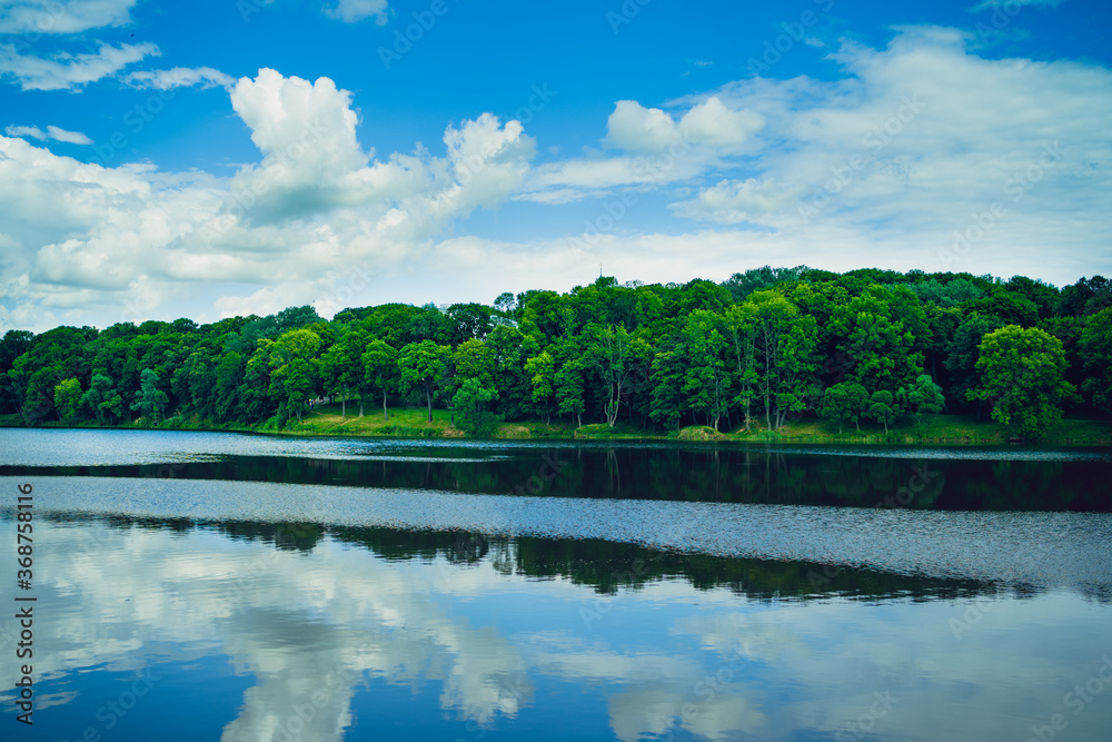 Calm pond in green countryside. Above amazing lake with tranquil water located near green forest in nature