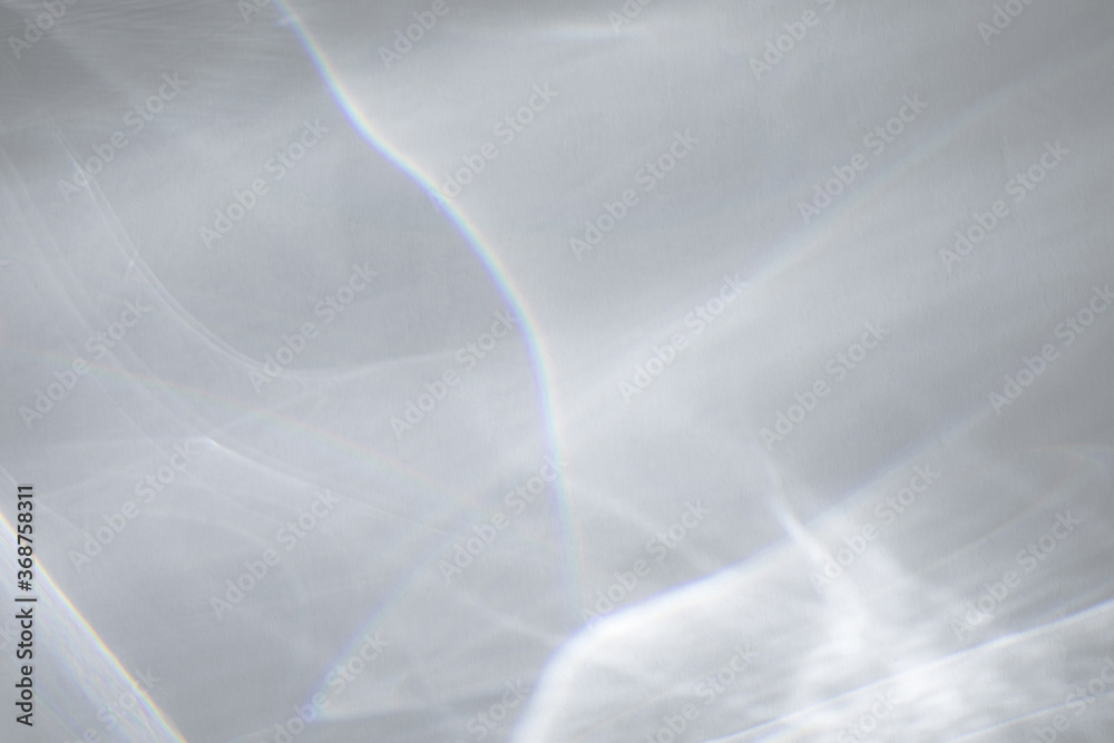 Obraz premium Blurred water texture overlay effect for photo and mockups. Organic drop diagonal shadow and light caustic effect on a white wall. Shadows for natural light effects