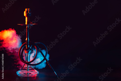 glass hookah shisha with a metal bowl on the table on a black background with smoke