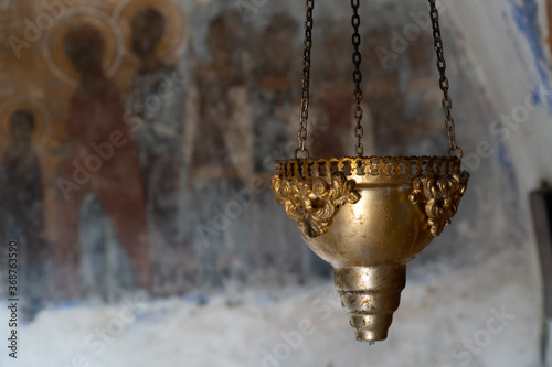 Old oil lamp in medieval chapel with blurred fresco in background, Paleochora - Aegina, Greece photo