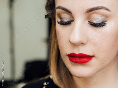 face of a woman with professional makeup with long eyelashes and red lipstick