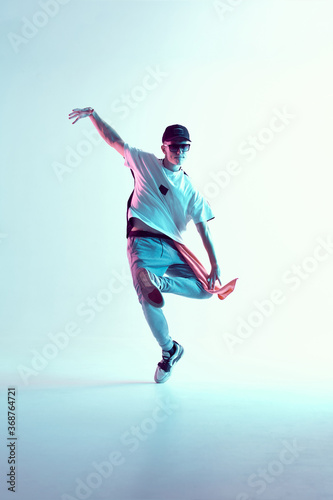 Boy dancing in neon light studio. Acrobatic dancer. Stylish flex.