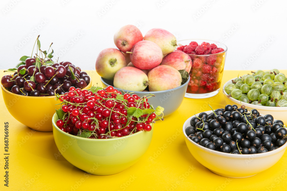 Fresh ripe vitamine berries and apples on yellow table: cherries, strawberries, gooseberries, redcurrant, blackcurrant Fresh ripe vitamine berries and apples on yellow table: cherries, strawberries, gooseberries, redcurrant, blackcurrant