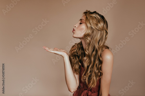 Gorgeous european young woman sending air kiss. Romantic curly girl expressing love.