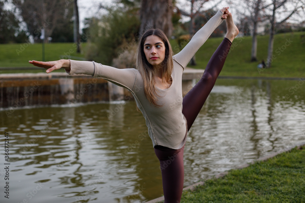 Yoga model stretching her body during a workout session at the park. Shot with natural light at sunset.